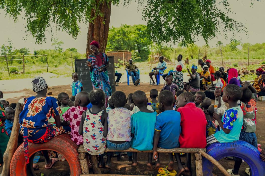 A class session under-a-tree at Limika Home Learning Center facilitated by caregiver Onzia Rabi. The center facilitates learning for over 120 children 